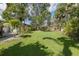 Green backyard featuring well-maintained lawn and diverse tropical landscaping enclosed by a wooden fence at 1830 Santa Barbara Dr, Dunedin, FL 34698