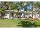 Charming single-story home with a lush green lawn, swaying palm trees, and a cozy seating area in the front yard at 1830 Santa Barbara Dr, Dunedin, FL 34698