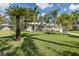 A charming single-story home with palm trees, a well-maintained lawn, and a cozy outdoor seating area at 1830 Santa Barbara Dr, Dunedin, FL 34698