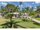Inviting single-story home with a lush green lawn, swaying palm trees, and a cozy seating area in the front yard at 1830 Santa Barbara Dr, Dunedin, FL 34698