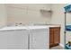 Practical laundry room with washer, dryer, sink, and storage shelves for organized convenience at 19326 Long Lake Ranch Blvd, Lutz, FL 33558