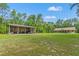 A house and large metal outbuilding are set on a large lot, surrounded by trees at 27295 Tarbel Rd, Brooksville, FL 34602