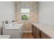 Bright laundry room with updated cabinets, countertop, and trendy wallpaper at 27295 Tarbel Rd, Brooksville, FL 34602