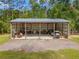 Large open air outbuilding with metal roof and gravel driveway surrounded by lawn and trees at 27295 Tarbel Rd, Brooksville, FL 34602