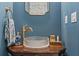 Elegant powder room boasts a glass vessel sink, brass fixtures, and dark blue walls at 27295 Tarbel Rd, Brooksville, FL 34602