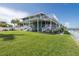 Back exterior showcasing a well-maintained lawn, screened porch, patio, and waterside location for outdoor enjoyment at 3150 Trident Ter, New Port Richey, FL 34652