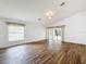 Living room features wood flooring, ceiling fan, neutral paint, and sliding door access to the enclosed porch at 3317 Abigail Ct, New Port Richey, FL 34655