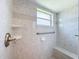 Close up of tiled shower with window, safety bar, and shower bench at 3317 Abigail Ct, New Port Richey, FL 34655