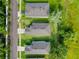 Aerial view showing three homes with well-kept lawns, neat landscaping, and dark grey shingle roofs at 4082 Watson Dr, New Port Richey, FL 34655