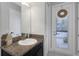 Well-lit bathroom featuring a granite vanity, contemporary fixtures, and a white door leading to the outside at 4287 Woodland Retreat Blvd, New Port Richey, FL 34655