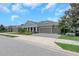 Street view of a beautifully landscaped one-story home with a three-car garage and paver driveway at 4287 Woodland Retreat Blvd, New Port Richey, FL 34655
