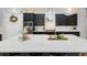 Elegant kitchen with a large white quartz island, stylish black cabinets, and stainless steel appliances at 4287 Woodland Retreat Blvd, New Port Richey, FL 34655
