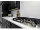 Kitchen cooktop with stainless steel burners, black cabinets, and modern countertops at 4287 Woodland Retreat Blvd, New Port Richey, FL 34655