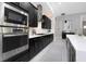 Gourmet kitchen featuring stainless steel appliances, gas cooktop, black cabinets, and tile flooring at 4287 Woodland Retreat Blvd, New Port Richey, FL 34655