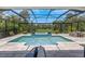 A beautiful in-ground pool sits inside of an enclosed screen with nature in the distance at 4287 Woodland Retreat Blvd, New Port Richey, FL 34655