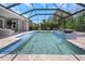 Relaxing backyard view of a screened pool area with spa fountains, travertine pavers, and lush landscaping at 4287 Woodland Retreat Blvd, New Port Richey, FL 34655