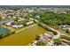 Aerial view showcases home on a lake in a neighborhood surrounded by green space and trees at 4716 Wolfram Ln, New Port Richey, FL 34653