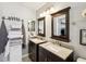 Bathroom with dual sinks, dark cabinets, light granite countertops, and a decorative mirror above each sink at 4716 Wolfram Ln, New Port Richey, FL 34653