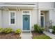 Close-up of the front porch with a wreath on the blue door, landscaping, and a 'HOME' welcome mat at 6240 Fairmont Ln, Palmetto, FL 34221