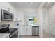 Modern kitchen with stainless steel appliances, white cabinets, counter space, and an open view to another room at 6240 Fairmont Ln, Palmetto, FL 34221