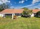 This home has a manicured backyard with green grass, a terra cotta roof, and a privacy fence at 7518 Mediterranean Ct, Hudson, FL 34667