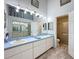 Bright bathroom featuring a double sink vanity with a light blue countertop and a glass-enclosed shower at 7518 Mediterranean Ct, Hudson, FL 34667