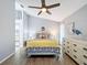 Bright bedroom with a ceiling fan, light gray walls, wood-look floors, and a glimpse of the bathroom at 7518 Mediterranean Ct, Hudson, FL 34667