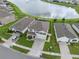Aerial view displays a beautiful home overlooking a serene lake, surrounded by lush green lawns and neighboring properties at 8938 Bower Bass Cir, Wesley Chapel, FL 33545