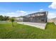 Green backyard with a screened-in patio and a small palm tree by a fence at 8938 Bower Bass Cir, Wesley Chapel, FL 33545