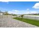 Landscaped backyard overlooking the lake features a paved patio and white picket fence at 8938 Bower Bass Cir, Wesley Chapel, FL 33545