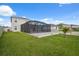 Spacious grassy backyard features an enclosed patio with views of neighboring homes at 8938 Bower Bass Cir, Wesley Chapel, FL 33545