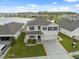 Aerial view of a lovely two-story home, a well-kept lawn and a tranquil lake view, blending serenity and style at 8938 Bower Bass Cir, Wesley Chapel, FL 33545