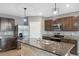 An eat-in kitchen with dark wood cabinets, granite countertops, stainless steel appliances, and a large island at 8938 Bower Bass Cir, Wesley Chapel, FL 33545
