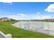 Scenic lake view showcasing the tranquil waterfront homes under a bright sky with scattered clouds at 8938 Bower Bass Cir, Wesley Chapel, FL 33545