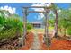 A backyard oasis features a screened pool enclosure viewed through an arched garden gate at 9130 Madrid Rd, Weeki Wachee, FL 34613
