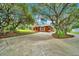 Expansive driveway leading to the house, surrounded by beautiful trees and landscaped areas at 9130 Madrid Rd, Weeki Wachee, FL 34613