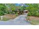 Long driveway leading to a charming home surrounded by lush greenery and mature trees at 9130 Madrid Rd, Weeki Wachee, FL 34613