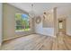 Bright living room with wood floors, a decorative chandelier, and a large window overlooking the front yard at 9130 Madrid Rd, Weeki Wachee, FL 34613
