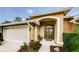Close-up of the front entrance featuring decorative sidelights, a covered porch, and a warm color palette at 9719 Oakwood Hills Ct, New Port Richey, FL 34655