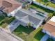 Aerial view of a home with gray roof, screened-in pool, and a long driveway leading to the attached garage at 10029 Freestone Ln, Port Richey, FL 34668