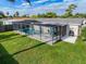 A pristine pool is enclosed by a screened cage and decorative curtains, with ample patio space and a grill at 10029 Freestone Ln, Port Richey, FL 34668