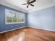 Bright bedroom with wood floors, blue walls, ceiling fan, and large window at 10097 Holly Berry Dr, Weeki Wachee, FL 34613