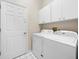 Functional laundry room with white washer, dryer and overhead cabinets for storage at 10097 Holly Berry Dr, Weeki Wachee, FL 34613