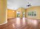 Bright living room with wood floors, yellow walls, vaulted ceilings, and sliding glass doors overlooking the green backyard at 10097 Holly Berry Dr, Weeki Wachee, FL 34613