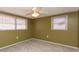 Bedroom featuring neutral carpet, ceiling fan, two windows, and olive-green colored walls at 10123 Oak Hill Dr, Port Richey, FL 34668