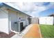 Exterior view of a side yard featuring access gate, air conditioner and gravel pathway at 10123 Oak Hill Dr, Port Richey, FL 34668