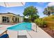 Inviting backyard with a sparkling pool, covered patio, lush greenery, and lounge chairs, perfect for relaxation at 10224 Old Orchard Ln, Port Richey, FL 34668