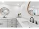 Bright bathroom features double sinks, granite countertops, white cabinetry, and round mirrors at 10224 Old Orchard Ln, Port Richey, FL 34668