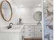 Bright bathroom features double sinks, granite countertops, white cabinetry, and round mirrors at 10224 Old Orchard Ln, Port Richey, FL 34668