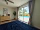 A bright bedroom offers a ceiling fan and sliding glass doors that lead to a large, screened-in private pool at 10224 Old Orchard Ln, Port Richey, FL 34668